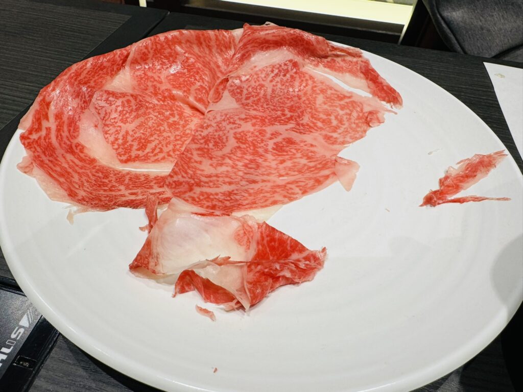 白い皿に盛られた霜降り肉の食べかけの写真(取り分け後で一部が残っている状態)