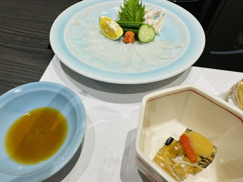 てっさの大皿とポン酢、小鉢のふぐ煮凝りが並ぶコースのスタート