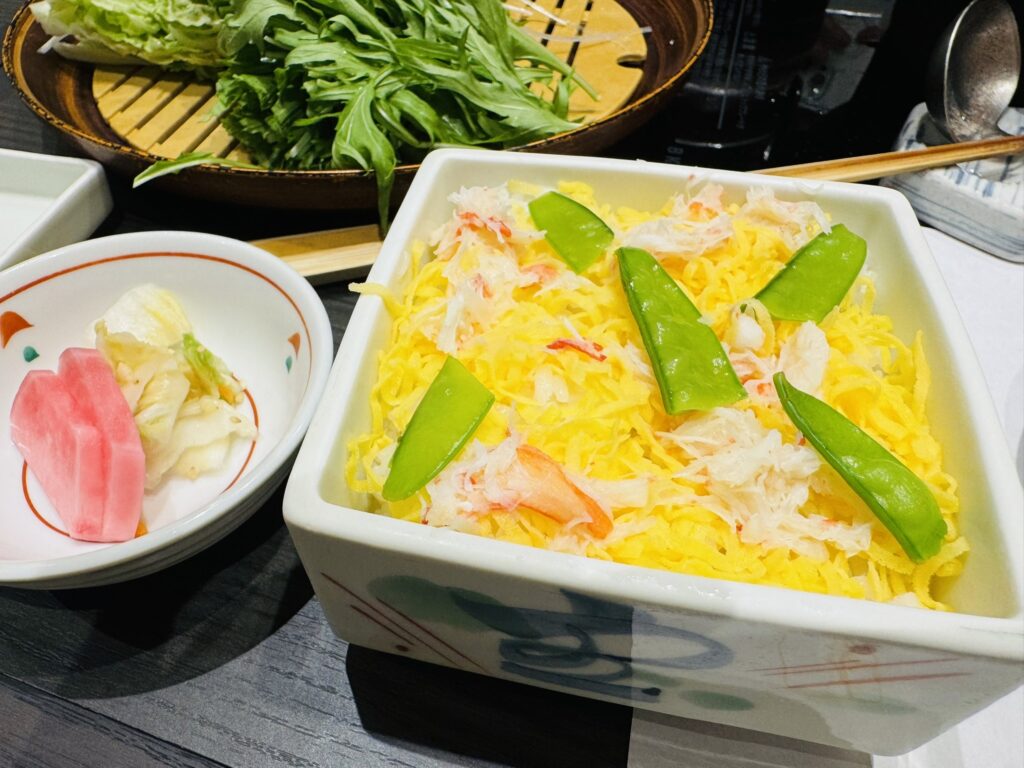 かに蒸し寿司の升と、横に添えられた香の物(漬物)