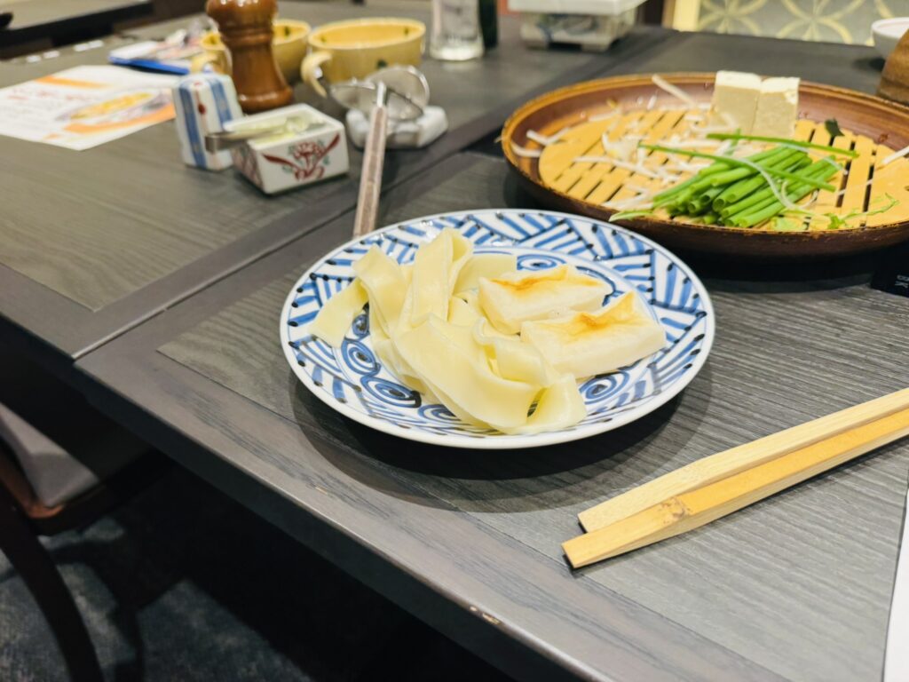 きしめんと焼き餅を皿に用意、奥に野菜の竹ざる