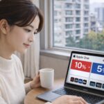 冬の室内で窓辺に座った日本人女性が、MacBookの画面に表示された10％と5％の比較ビジュアルを見つめながら静かに検討している様子。