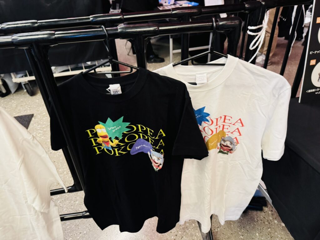 物販で展示されている黒と白のTシャツ（ロゴデザイン入り）