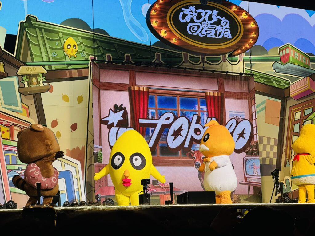 ステージ上のキャラクターたちが並ぶシーン、観客越しに撮影